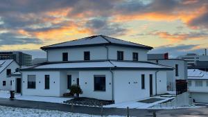 a white house with a sunset in the background at Villa LaLeo in Künzelsau