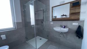 a bathroom with a glass shower and a sink at Villa LaLeo in Künzelsau +3 photos