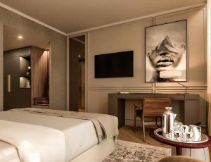 a bedroom with a bed and a desk and a television at Hotel Atlantiis Suites Near Kashi Vishwanath temple in Varanasi