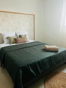 a large bed with green sheets and pillows on it at Villa Canne & Ô in Saint-Joseph