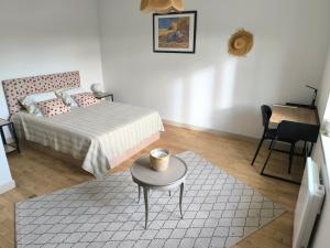a bedroom with a bed and a table and a desk at Maison de Jules in Le Coteau