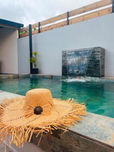 a straw hat sitting on the edge of a swimming pool at Villa Canne & Ô in Saint-Joseph