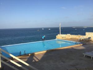 una persona si trova in una piscina vicino all'oceano di Residenz Stella Maris Apartment Strela a Calheta Do Maio