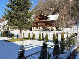 a house in the snow with a fence and christmas trees at Deine Auszeit mit Alpenblick in Kandergrund