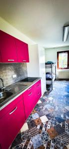 een keuken met rode kasten en een tegelvloer bij Nertha, die Ferienwohnung in Uslar