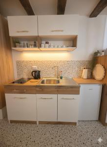 una cucina con mobili bianchi e un lavandino di Apartman Mona a Sarajevo