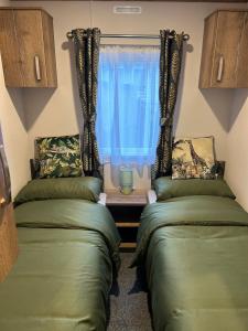 two beds in a room with a window at Annas Escape Burnside Moray in Fochabers