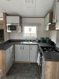 a kitchen with white cabinets and a stove top oven at Annas Escape Burnside Moray in Fochabers