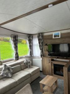a living room with a couch and a flat screen tv at Annas Escape Burnside Moray in Fochabers
