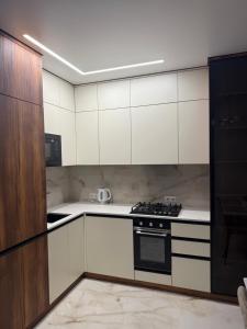 una cucina con mobili bianchi e un forno a piano cottura di Apartment Uman a Umanʼ