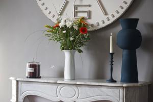 a table with a vase of flowers and a mirror at La Villa Côté Cour in Dinan