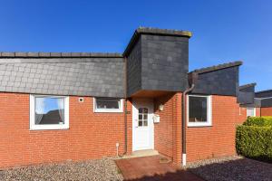 a red brick house with a black roof at Ferienhaus Wolke 7 in Bensersiel