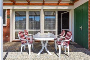 a white table and four chairs on a patio at Ferienhaus Wolke 7 in Bensersiel