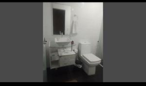 a white bathroom with a toilet and a sink at Aluguel de Temporada in Arroio do Sal