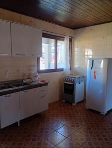 a kitchen with a white refrigerator and a stove at Aluguel de Temporada in Arroio do Sal