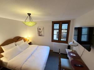 a bedroom with a bed and a desk and a chandelier at Hôtel Le Sarment d'Or in Riquewihr