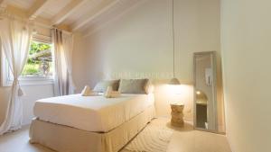 a white bedroom with a bed and a mirror at Villa Sara - Porto Cervo - 2 Private Beaches & Garden - by Coral Property in Porto Cervo