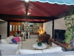 a living room with white couches and a tv at Pousada Casa de Campo in Conservatória