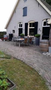 a patio with chairs and a table in front of a building at De Veldhoeve in Apeldoorn