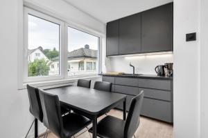 a kitchen with a black table and chairs and a window at Oddernesveien 7 in Kristiansand