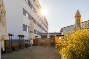 een gebouw met parasols en de zon die schijnt bij Hotel 22 in Dessau