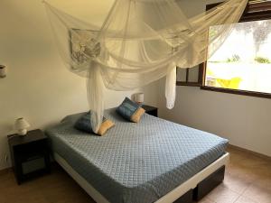 a bedroom with a bed with a canopy and a window at Villa CosaRoé-Vue Mer-Piscine-3 étoiles in Rivière-Salée