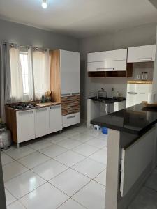 a kitchen with white cabinets and black counter tops at Casa in São Raimundo Nonato
