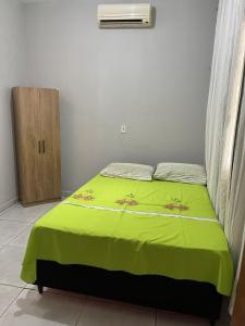 a bedroom with a bed with a green blanket at Casa in São Raimundo Nonato