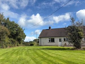 a house with a green lawn in front of it at Orchard Cottage in Loughgall