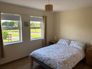 a bedroom with a bed and two windows at Orchard Cottage in Loughgall