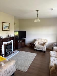 a living room with two chairs and a fireplace at Orchard Cottage in Loughgall