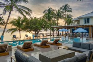 a resort with a pool with chairs and palm trees at Blue Reef Beach and Marina in Placencia