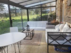 een serre met een bank en een tafel en stoelen bij Maison au calme Plessala Le Mené in Saint-Udy