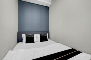 a small bedroom with a white bed with two pillows at Collection O Yayah Residence in Bogor