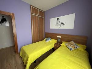 two beds in a room with yellow sheets at El Arca de Noé in Luarca