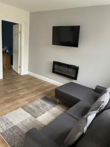 a living room with a black couch and a flat screen tv at Greenway Cottage in Baltonʼs Cross Roads