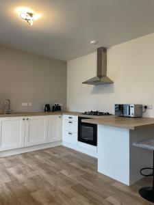 a kitchen with white cabinets and a stove top oven at Greenway Cottage in Baltonʼs Cross Roads