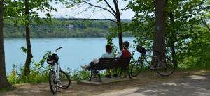 two people sitting on a bench near a river with bikes at Charlotte Garden Bed and Breakfast in Niagara on the Lake