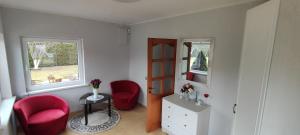a room with two red chairs and a window at Pakeliui I -On the way I in Baltrušaičiai