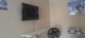 a tv on a wall with a table and a fan at Nteto guesthouse in Dwarsloop