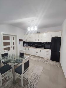 a kitchen with a glass table and white cabinets at Zafir Apartment in Korçë