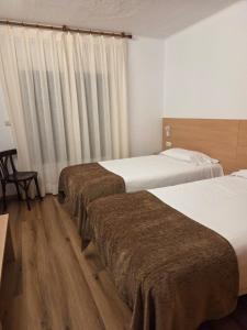 una camera d'albergo con due letti e una finestra di Apartaments Turistics Pirineu a Soldeu