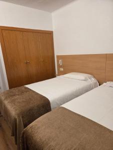 una camera con due letti e armadi in legno di Apartaments Turistics Pirineu a Soldeu