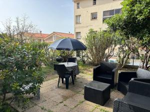 a patio with a table and chairs and an umbrella at Appartement plein centre avec jardin de 40m2 près des plages in Propriano