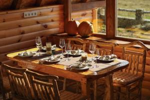 a wooden table with chairs and wine glasses at Vikendica Pino in Han Pijesak