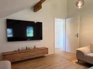 a living room with a large flat screen tv on the wall at Deine Auszeit mit Alpen- und Kanderblick in Kandergrund