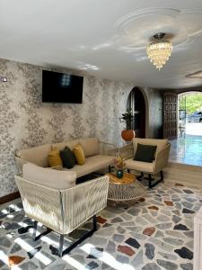 a living room with a couch and chairs and a tv at Casa Marina Hotel Boutique in Ríohacha
