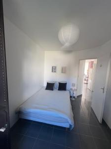 een slaapkamer met een wit bed met 2 kussens bij Maison entière avec jardin , Proche Bordeaux, Rocade et Arkéa Arena in Bouliac