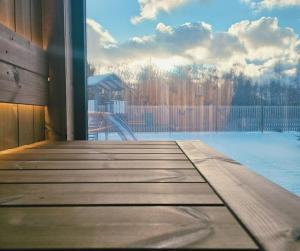 een houten terras met uitzicht op een zwembad bij Kursīšu namiņš in Skulte