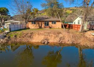 a house sitting on top of a body of water at Lakefront Retreat • Private Yard + Fireplace in Clearlake Oaks